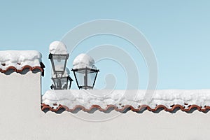 Snow on fence of house and lantern, blue sky on sunny day on street of town. Winter concept, background, copy space