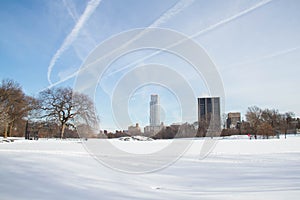 Snow field at park with blue sky and buildings