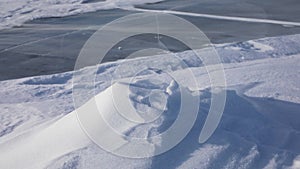 Snow flying over surface of blue ice of Lake Baikal