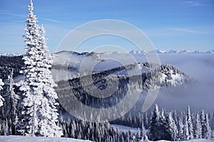 Snow ghost overlooking cloud-blanketed valley and Peaks Peeking above it at Whitefish Resort