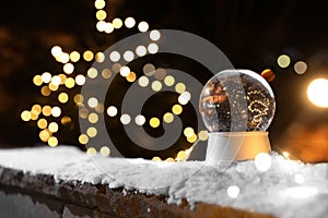 Snow globe and blurred Christmas lights on background