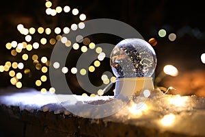 Snow globe and blurred Christmas lights on background