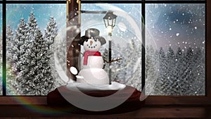 Snow globe on windowsill looking out to snowy forest