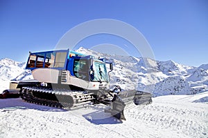 Snow grooming machine on snow hill ready for skiing slope preparations in Alps, Europe ski resort