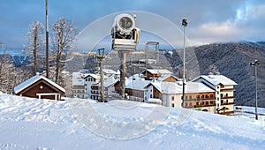 Snow gun about of cottages in mountains