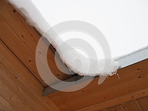 Snow is hanging from the roof of the house