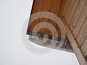 Snow is hanging from the roof of the house