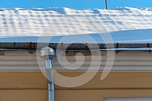 Snow and ice on the roofs of buildings. Icicles hang from the roofs of houses. The probability of the roof collapsing under the