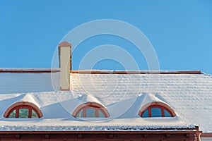 Snow and ice on the roofs of buildings. Icicles hang from the roofs of houses. The probability of the roof collapsing under the