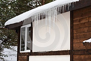 Snow with icicles on the roof of a guest house in the forest