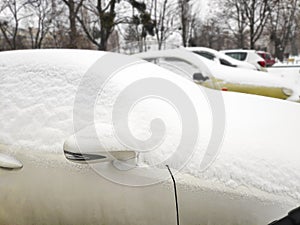 Snow layer on windscreen, window of sedan in city street driveway parking lot spot. car stuck after heavy blizzard