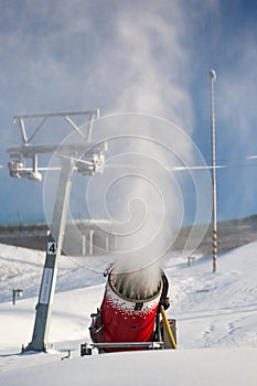 Snow-machine bursting artificial snow over a skiing slope