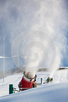 Snow-machine bursting artificial snow over a skiing slope