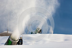 Snow-machine bursting artificial snow over a skiing slope