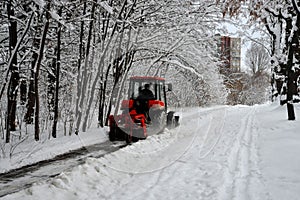 Snow machine, red tractor cleans the snow from the snow in the background of the forest.