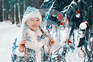 Snow Maiden. portrait of a little girl with pigtails in the forest near the New Year tree. fairy tale