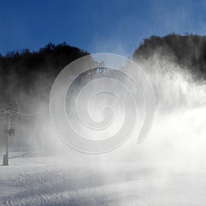 Snow making machines blast cold snow clouds on the ski slope