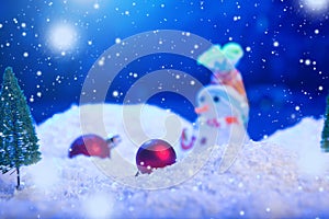 Snow Man with Christmas balls on snow over fir-tree, night sky and moon. Shallow depth of field. Christmas background