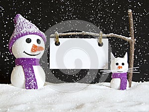 Snow man and snow cat with sign