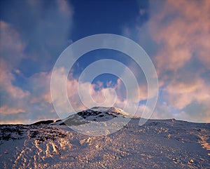 Snow mountain at sunset with some clouds.