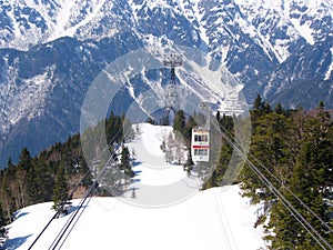 A Snow Mountain view from Shinhotaka Ropeway in Gifu Prefecture mountain park on spring day with green pine trees forest. Takayama