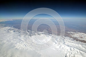 Snow mountains winter landscape from the plane in stratosphere with dark blue sky