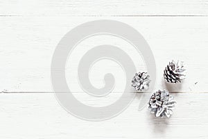 Snow painted pine cones on rustic white wood table. Christmas de