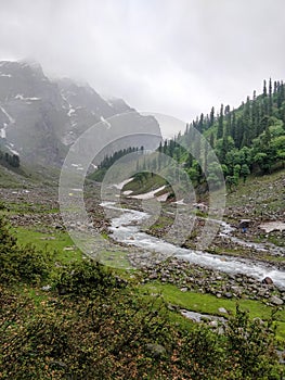 Snow patches and river stream flowing through rocks in an epic Indian Himalayan Mountain Valley.