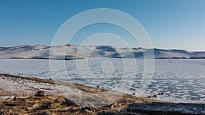 Snow patterns and several minibuses are visible on the surface of the frozen lake photo