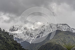 Snow and peaks loom out of clouds at Franz Josef Waiau, West Coast, New Zealand