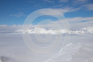 Snow peaks over clouds. Caucasus rocks. White mountains and blue sky.