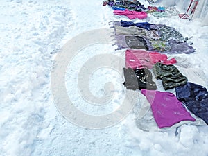 In the snow, people sell things. Flea market in winter. The clothing market right on the ground is winter. On the snow