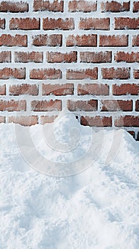 Snow pile in front of brick wall