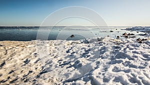 Snow pile, hill. Large snow drift  on a blue sky background,  outdoor view of ice blocks at frozen finland lake in winter