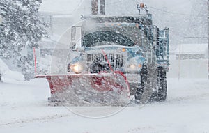 Snow plow with a red plow working in a blizzard