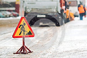 Snow-plow remove snow from the city street.Warning road sign.Winter service vehicle snow blower work.Cleaning snowy