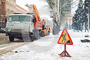 Snow-plow remove snow from the city street.Warning road sign.Winter service vehicle snow blower work.Cleaning snowy