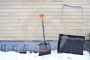 Snow plow and snow shovel leaning against a wall