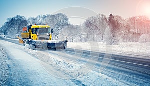 Snow plow truck clearing snowy road after snowstorm