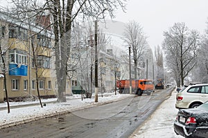 Snow removal. An orange truck and a tractor are cleaning the roa