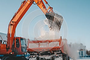 Snow removal after snowfall and blizzards. Excavator loads snow into a truck