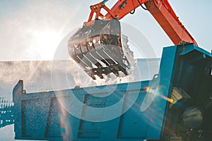 Snow removal after snowfall and blizzards. Excavator loads snow into a truck