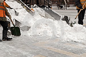 Snow removal on the streets. Close-up of a snowplow and road workers with shovels. People and cars. Abundance of snow. Winter