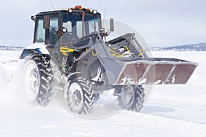 Snow removal vehicle on the road. Snow plow tractor is cleaning a city after snowstorm