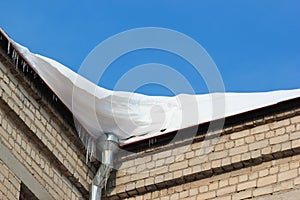 Snow on roof with winter gutter and icicles