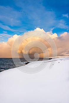 Snow and sea: the snow arrives all the way to the shoreline of an unfrozen deep blue sea