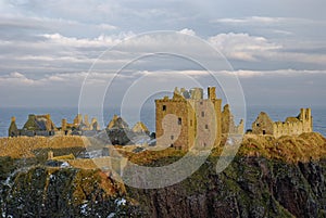 Snow seen on the cliffs on which Dunnottar Castle lies, lit up in the Golden Evening Sun of a cold Winters day