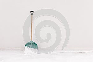 Snow shovel propped against the white wall of the house