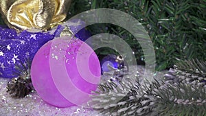 Snow slowly falls on New Year`s balls against the background of a Christmas fir-tree. slow motion