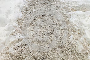 Snow slush with dirt and footprints on the road in snowdrift